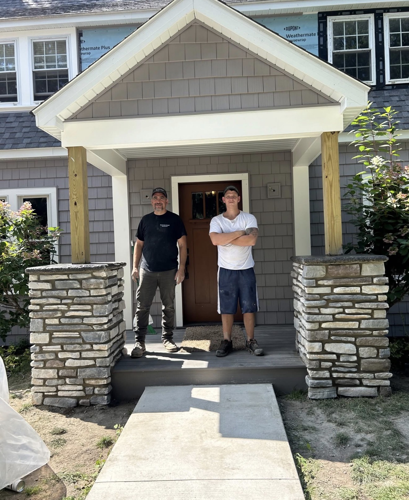 Two crew members on a porch with finished stone columns