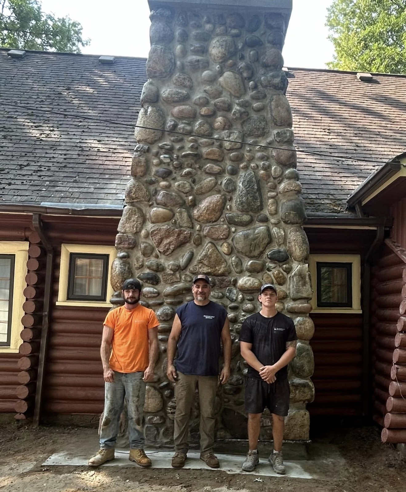 Crew standing in front of a finished river-rock stone chimney